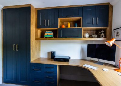 Image of a home office with desk, elevated cupboards units and drawers