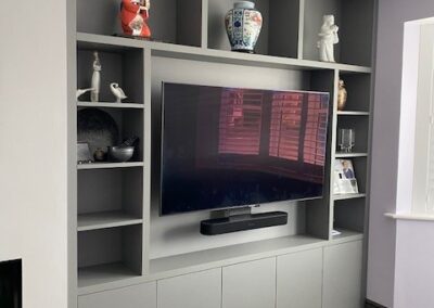 Image of a living room with a grey media unit and shelving